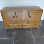 An Ercol Golden Dawn elm sideboard with three cupboards above two drawers - good condition, some