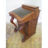 A Victorian burr walnut Davenport with a shaped front and carved scroll supports - four active and