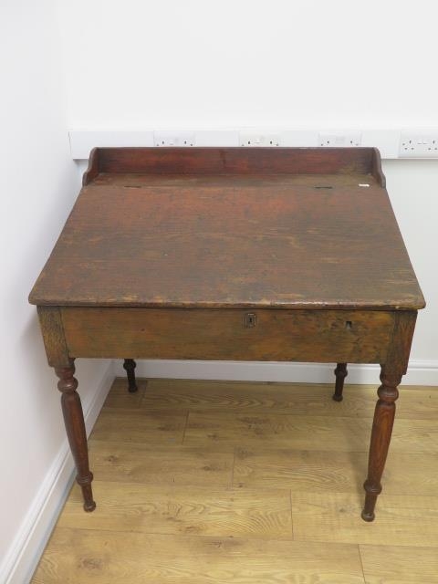 A 19th century clerks desk with lift up sloping top on turned legs, 105cm tall x 99cm x 70cm