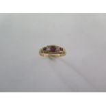A ruby and diamond half hoop ring - cast scrolled shoulders and bezel set with three mixed cut