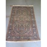 A fine woven silk mix rug with cream field foliate centre with stylized boarder - 192cm x 122cm -