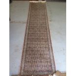 A woven runner rug with a faded pink field - 315cm x 78cm - some fading but generally good