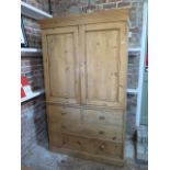 A Victorian stripped pine linen press with a two door top enclosing two slides above a four drawer