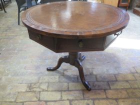 An oak circular drum table with leather inset top over a hexagonal frieze with three active