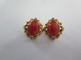 A pair of Mediterranean coral stud earrings, oval cabochon cut, rub over set in a scalloped