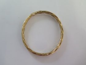 A 9ct yellow gold hinged bangle - 6cm x 6.5cm external - approx weight 8.3 grams - some usage wear