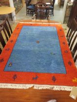 A woollen rug with a blue field and orange border - 192cm x 122cm - in good condition