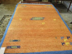 A woollen rug with an orange field - some wear to edges - 197cm x 129cm