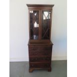 A mahogany bookcase chest with a two door astragal glazed top over a four drawer chest with a