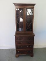 A mahogany bookcase chest with a two door astragal glazed top over a four drawer chest with a