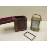 An oval brass carriage clock with travel case - replacement door, no key