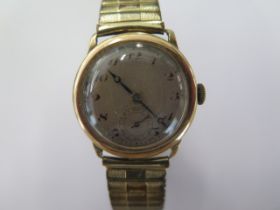A 9ct yellow gold manual wind wristwatch on a plated sprung strap - 28mm case - total weight