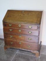 A Georgian elm four drawer bureau with a fitted interior on shaped bracket feet - Height 107cm x