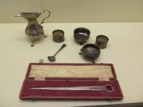 A silver skewer letter opener, silver cream jug, two napkin rings, two salts and a spoon - total