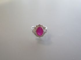 An 18ct white gold ring set with an oval ruby, surrounded by a halo of round brilliant cut and