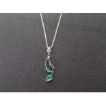 An 18ct white gold and emerald pendant and chain - three emeralds set in leaf shape - pendant approx