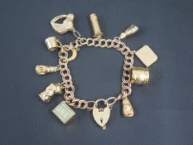 A 9ct yellow gold charm bracelet, eleven charms and lock, all hallmarked - weight approx 34 grams