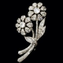 A stunning platinum and diamond flower brooch, set with round brilliant cut and baguette