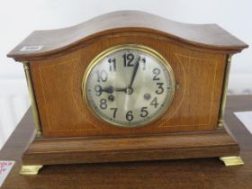 An oak mantle clock with turned pillars and glass front