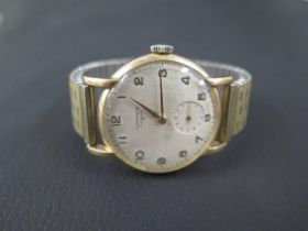 A gents 9ct gold Longines wristwatch with a plated strap and seconds hand - in working order