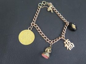 A 9ct rose gold charm bracelet with fine charms including a George III 1776 gold spade Guinea -
