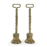 A PAIR OF BRASS LION'S PAW DOORSTOPS IN REGENCY STYLE, 19TH CENTURY with foliate stems and