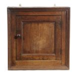 A GEORGE III OAK HANGING CUPBOARD LATE 18TH CENTURY with a panelled door enclosing a shelf 61cm