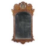 A GEORGE II WALNUT FRET-FRAME WALL MIRROR C.1735-40 the later arched bevelled plate, within a carved