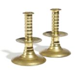 A NEAR PAIR OF BRASS TRUMPET CANDLESTICKS C.1650-1680 each with a ribbed stem, central drip-pan