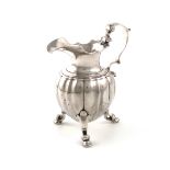 An 18th century cast silver cream jug, unmarked, circa 1740, lobed baluster form, leaf capped scroll
