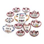 A collection of twelve enamelled wine labels, including a matched set of five titled 'PEACH