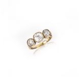 A diamond three stone ring, the three graduated old cushion-shaped diamonds rubover-set in gold,