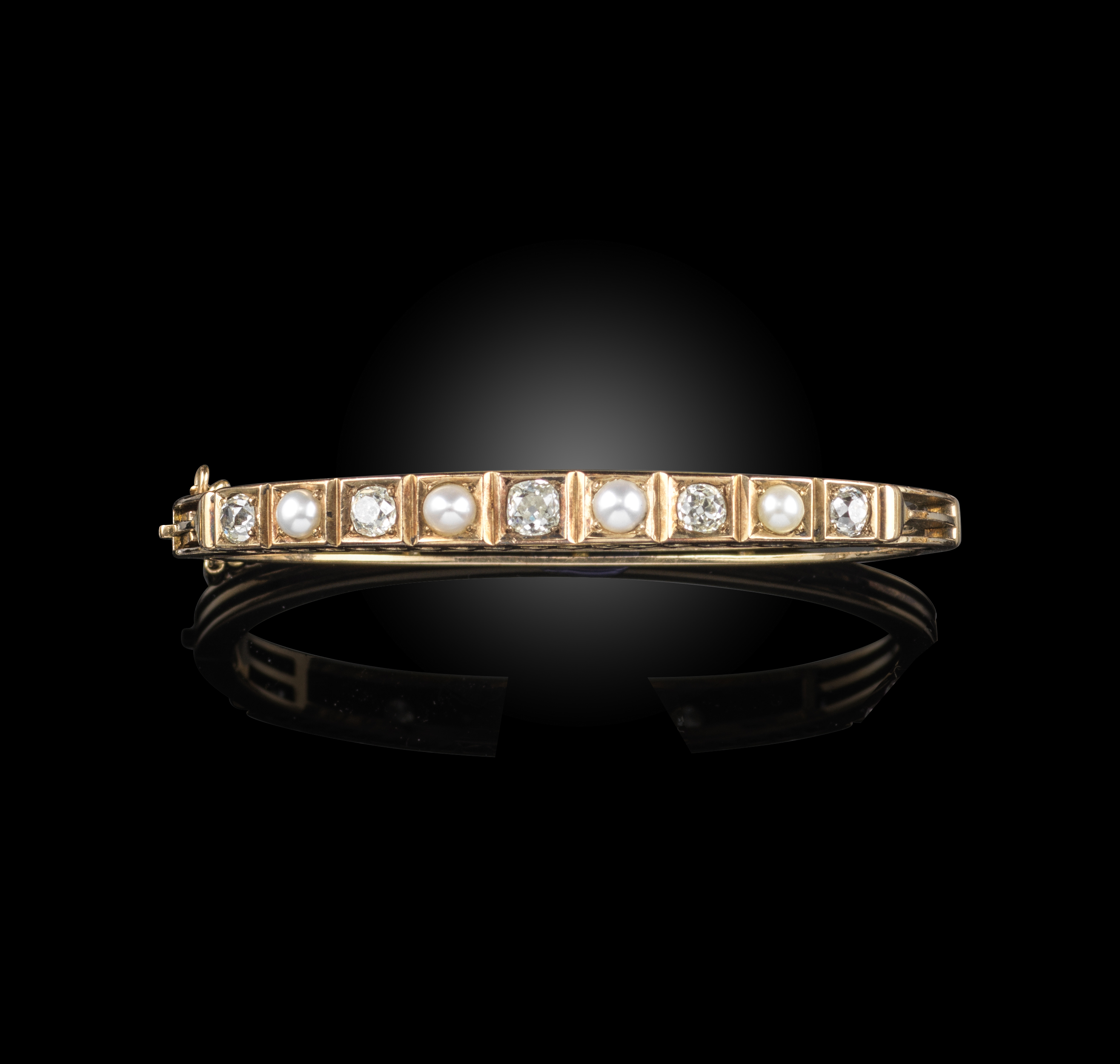 A late 19th century pearl and diamond bangle, alternately-set with cushion-shaped diamonds and