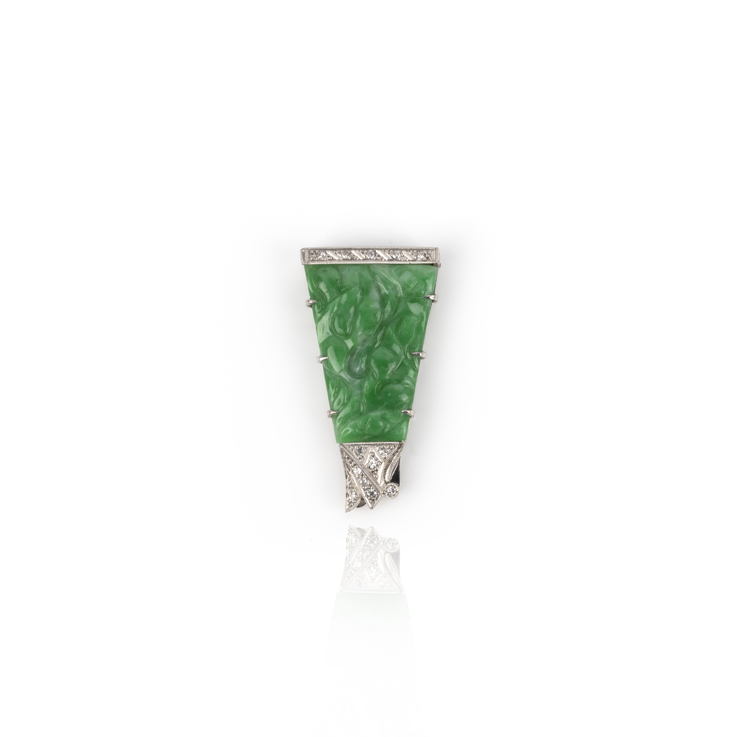 An Art Deco jadeite and diamond clip brooch, circa 1930, of triangular outline, set with a carved