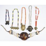 Six Naga head chest ornaments Nagaland five on glass bead necklaces, including four brass, one