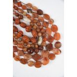 Seven Indian / Naga carnelian bead necklaces spherical, ribbed and flat beads, one with brass beads,