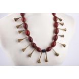 A Naga necklace Nagaland glass beads, brass trumpet pendants and a shell clasp. 67cm long.