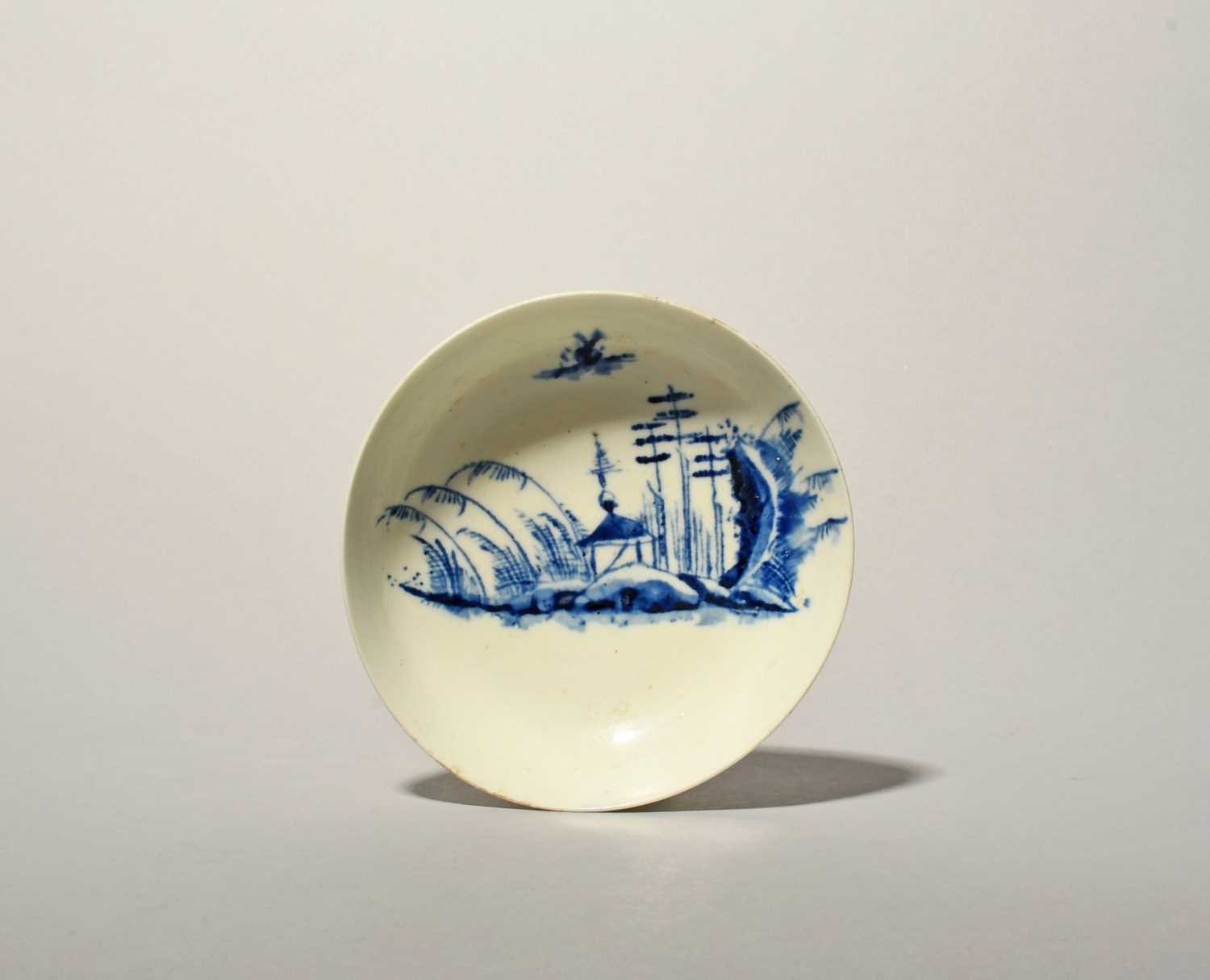 A Longton Hall or West Pans blue and white saucer, c.1760-65, painted with a Chinese landscape