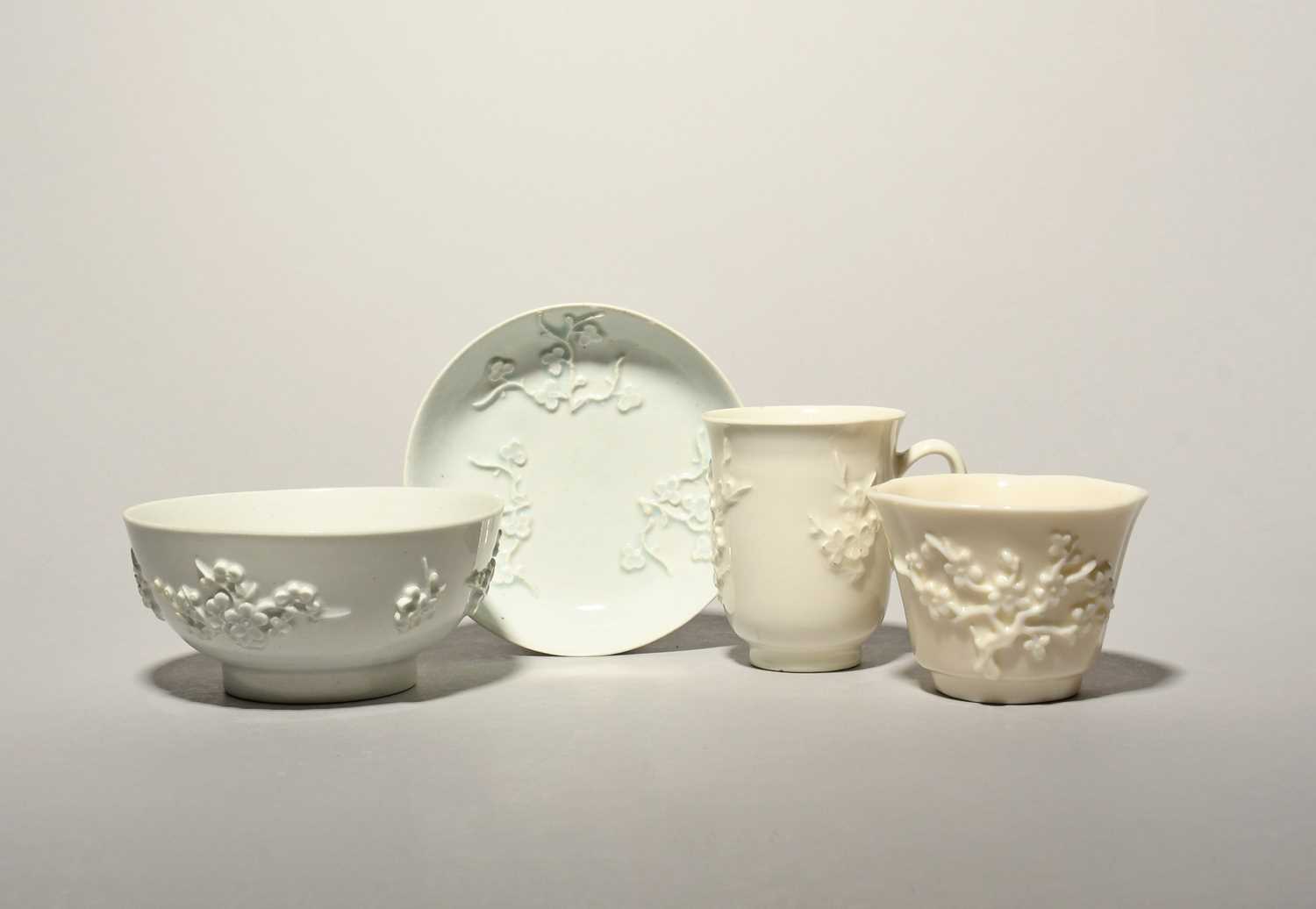 A Bow white-glazed chocolate cup, a saucer and a slop bowl, c.1752-55, the cup and bowl sprigged