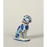 A delftware model of a dog, dated 1760, seated on its haunches on an oval pad base, its head