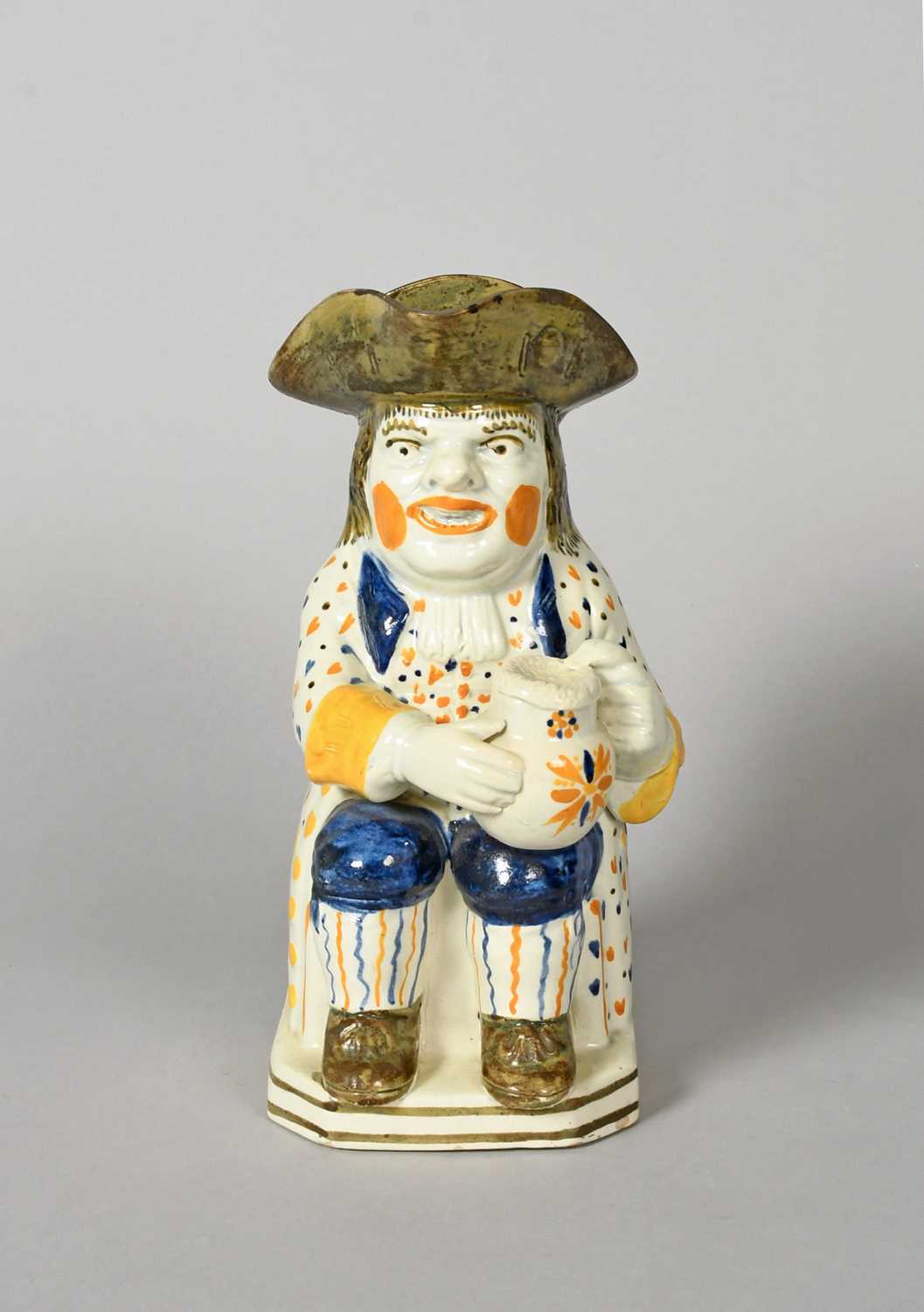 A Pratt ware 'Convict' Toby jug, c.1800, seated with a foaming jug of ale on his left knee,