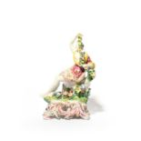A rare Bow figure of Flora, c.1765, reclining on a rocky stump and holding a garland of flowers