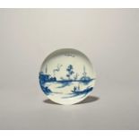 A rare Longton Hall blue and white saucer, c.1755-60, painted with the 'Ruined Castle' pattern, a