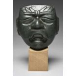 An Olmec style serpentine maskwith a relief carved brow, curved slit eyes and a were-jaguar mouth,