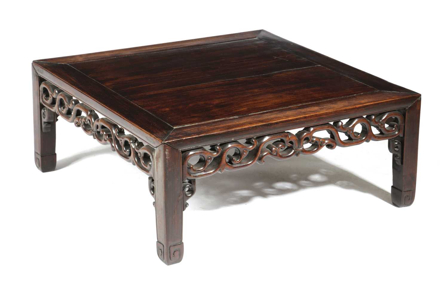 A CHINESE HARDWOOD LOW TABLE LATE 19TH CENTURY the panelled top above a pierced scrolling frieze