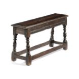 AN OAK LONG STOOL IN JACOBEAN STYLE, PROBABLY 19TH CENTURY on turned legs united by peripheral