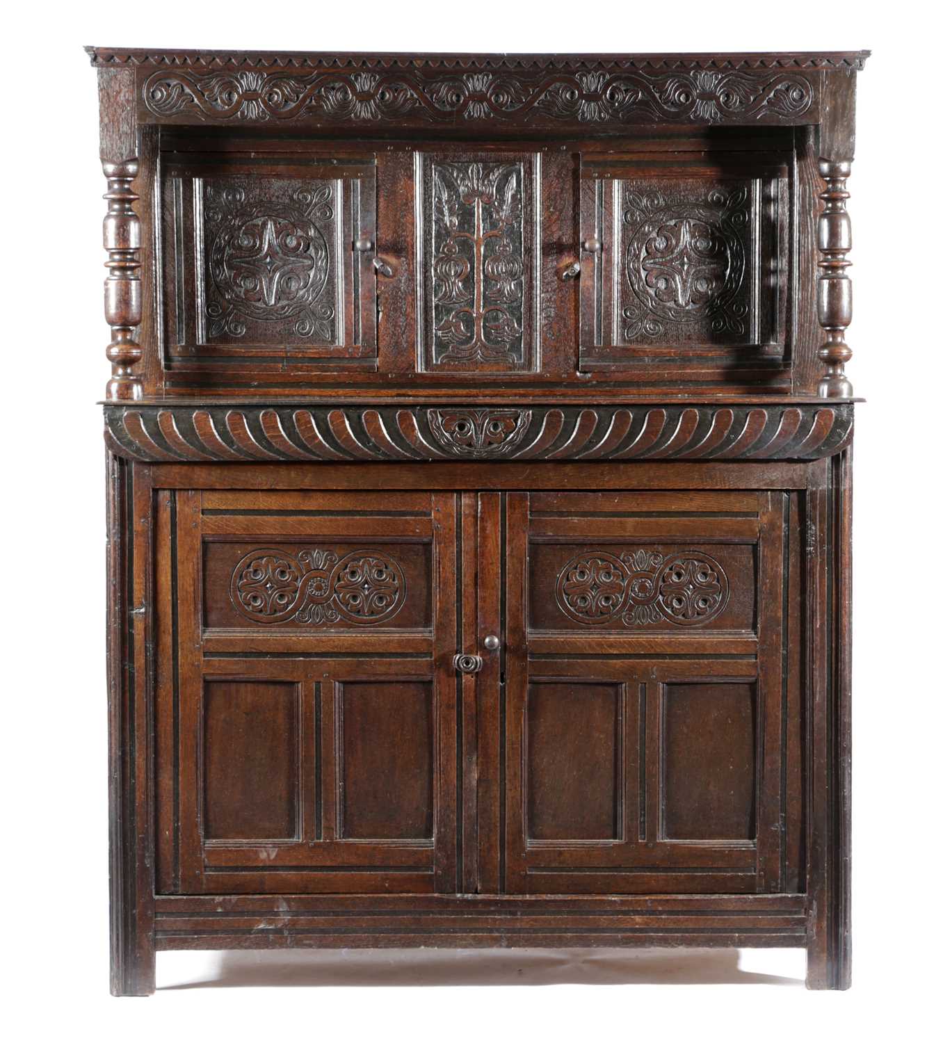 A CHARLES II OAK COURT CUPBOARD C.1680 carved with scrolling rondels and flowerheads, with a pair of