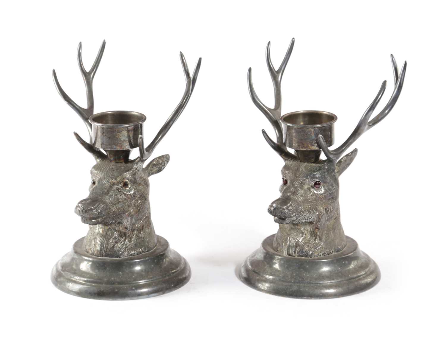 A PAIR OF SILVER PLATED STAG'S HEAD CANDLE HOLDERS 20TH CENTURY with glass eyes, each with a