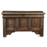 A JAMES I OAK COFFER EARLY 17TH CENTURY the planked top above a frieze with meandering foliage,