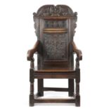 A CHARLES II OAK PANEL BACK ARMCHAIR YORKSHIRE, C.1680 the scroll crest decorated with leaves, the
